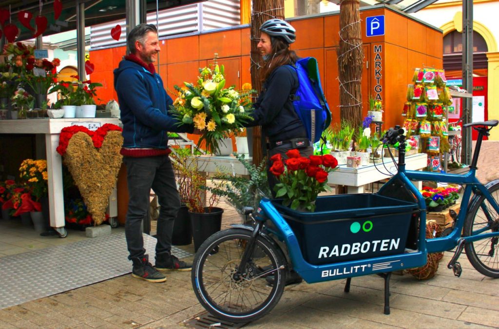 Frau holt Blumen für die Lieferung mti den Radboten ab